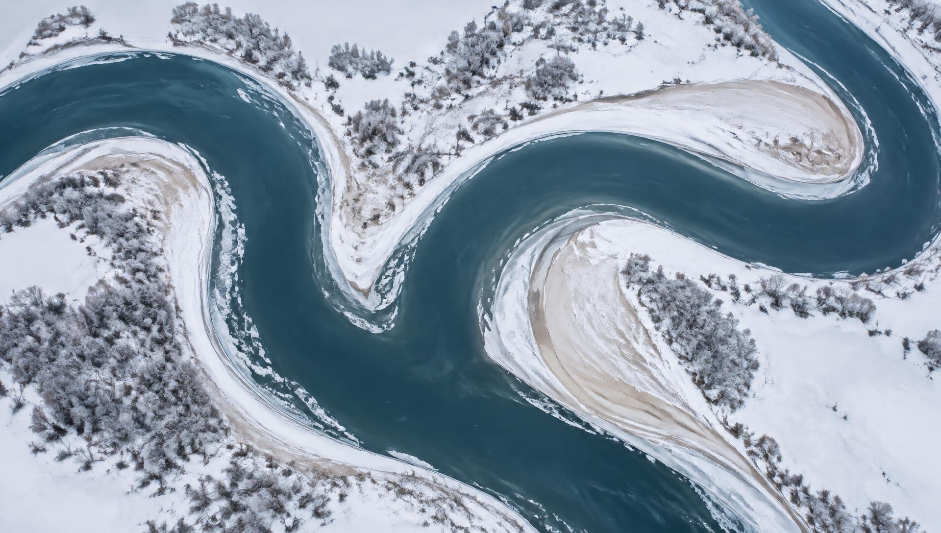 Luchtfoto van een rivier die in diepe S-bochten door een besneeuwd landschap meandert